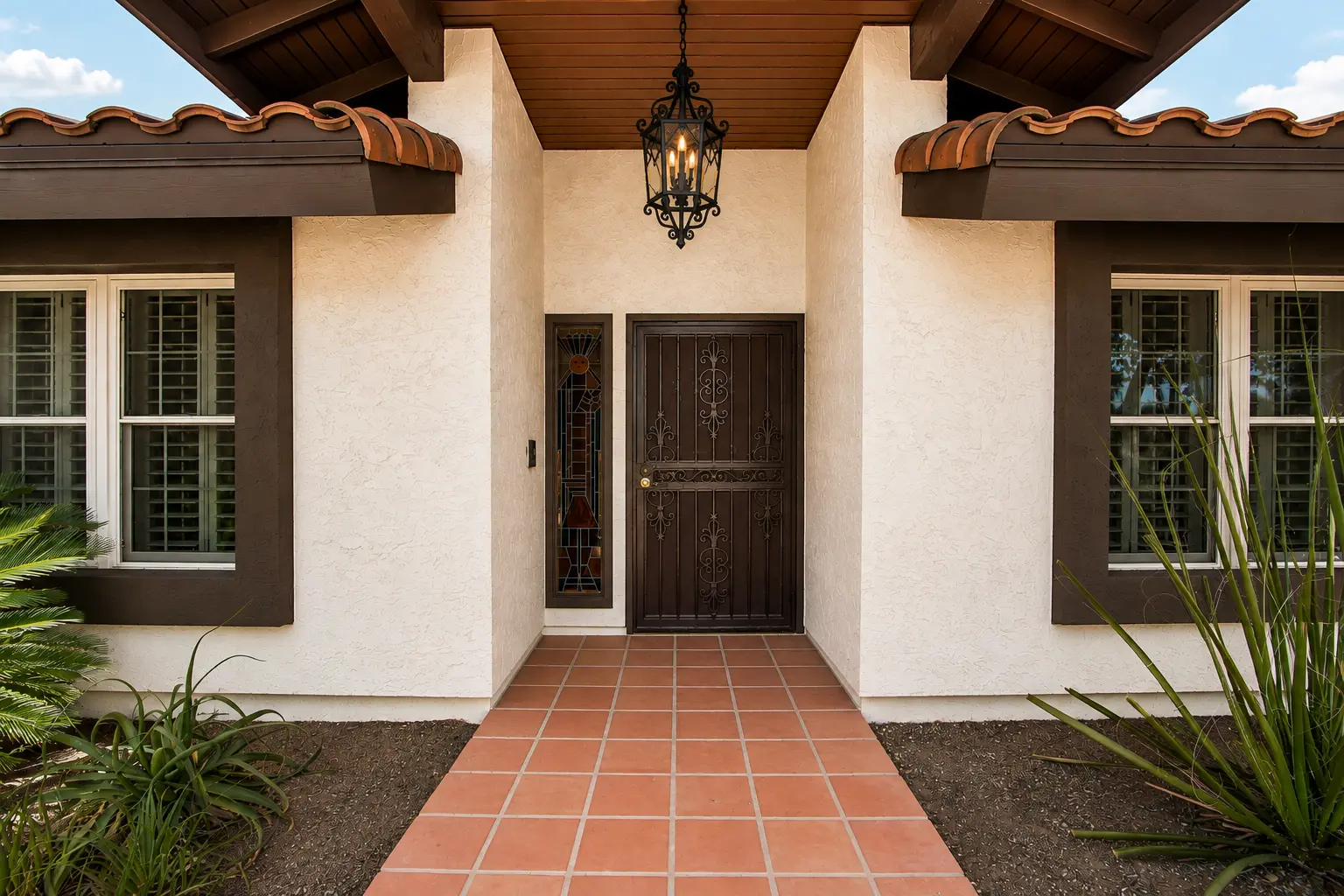 Front entry of 618 N La Loma Avenue with a wrought iron door, tile walkway, and hanging lantern